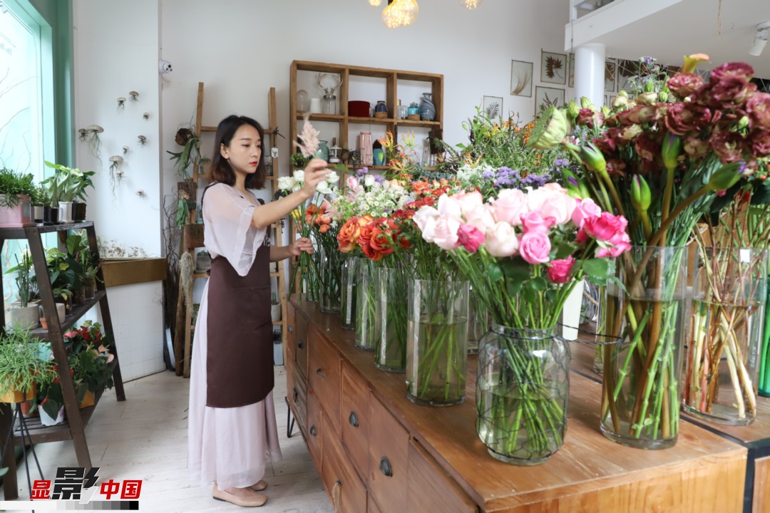 王黎媛是一名河南姑娘，在昆明念完大學(xué)后，就再也舍不下春城的藍(lán)天陽光、青山碧水，更舍不下這里的四時(shí)繁花，于是就干脆留了下來，成了一名媒體人。2017年的時(shí)候又毅然辭去工作，創(chuàng)業(yè)開起了花店，成了都市里的一名“花房姑娘”。圖為王黎媛在自己的花店中整理鮮花。新華網(wǎng) 周亞平/攝 念新洪/文